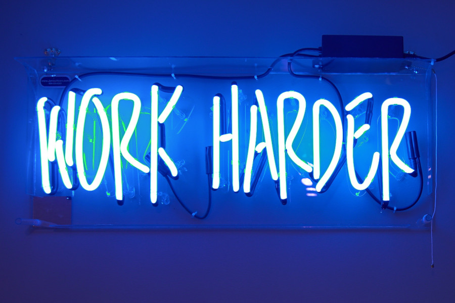 Neon sign showing the words 'work harder'